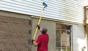Mike uses a soft-bristled brush to clean the siding on a home.